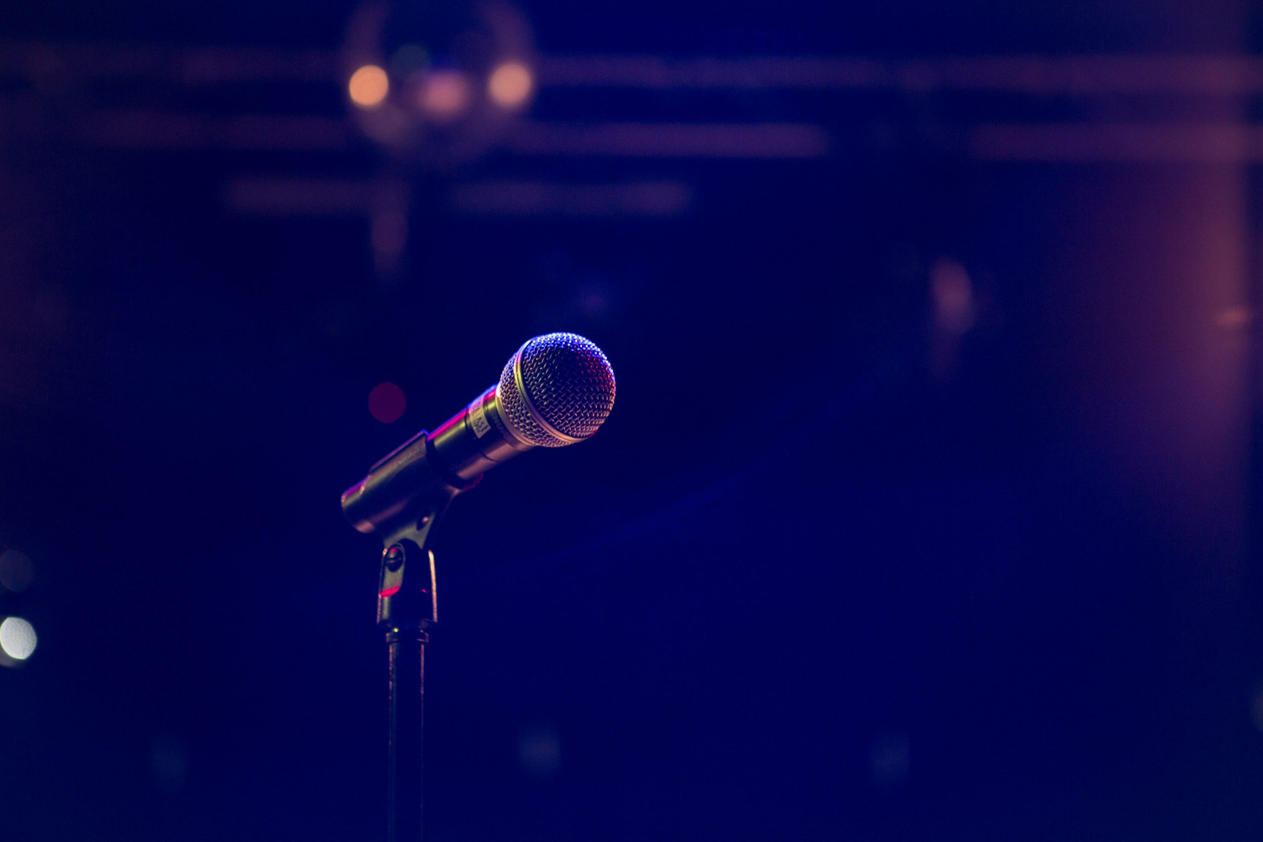Stock Image of a Microphone in a dark room - Photo by Matthias Wagner on Unsplash